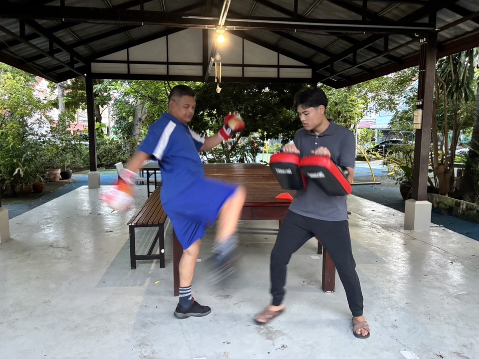 เทรนเนอร์ส่วนตัวกำลังสอนศิลปะการต่อสู้ให้ลูกศิษย์ ดูแลการฝึกสอนเพื่อลดน้ำหนักและเสริมสร้างกล้าม