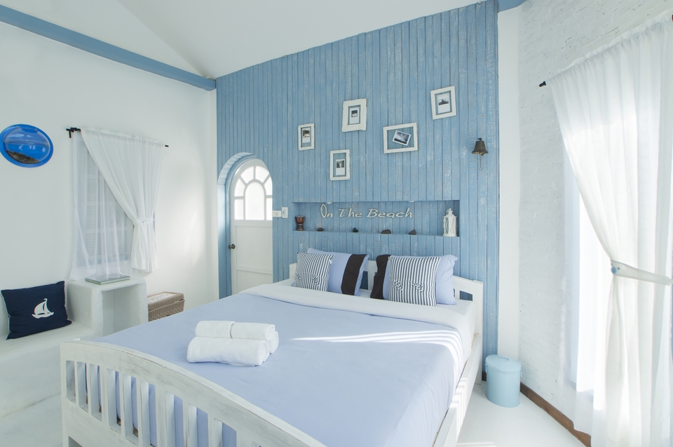 ตากล้อง รับถ่ายรูปบ้านสวยสไตล์ทะเล ในห้องนอนโทนสีฟ้าขาว มีหน้าต่างและผ้าม่านสีขาว