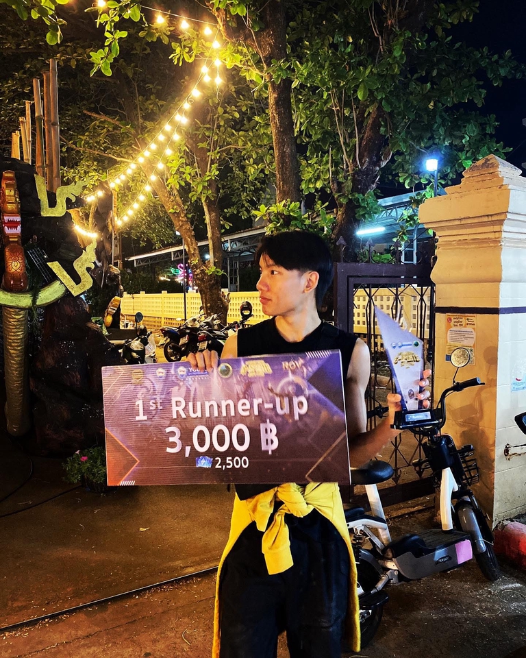 รับจ้างเล่นเกม รับปั้มแรงค์ rov หนุ่มถือป้ายรางวัล "1st Runner-up" 3,000 บาท พร้อมจักรยานยนต์และบรรยากาศไฟสวยงาม เหมาะสำหรับบริการรับจ้างเล่นเกม rov และรับปั้มแรงค์ rov, บริการเก็บเวล, รับดูแลไอดี, ไต่แรงค์