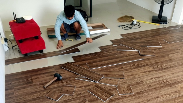 ปูกระเบื้อง ราคา ช่างปูกระเบื้อง กำลังติดตั้งพื้นกระเบื้องลายไม้ในบ้าน