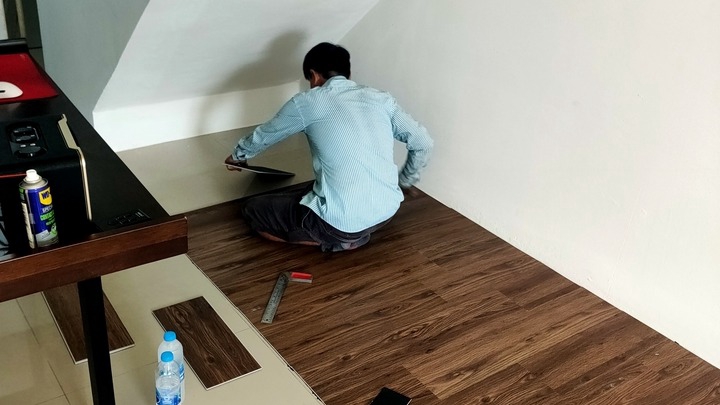 ปูกระเบื้อง ช่างปูกระเบื้องกำลังปูพื้นด้วยกระเบื้องลายไม้ในห้อง