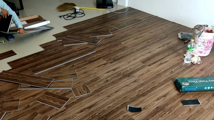 กำลังติดตั้งพื้นปูกระเบื้องลายไม้สวยงาม มีทั้งแผ่นกระเบื้องวางอยู่