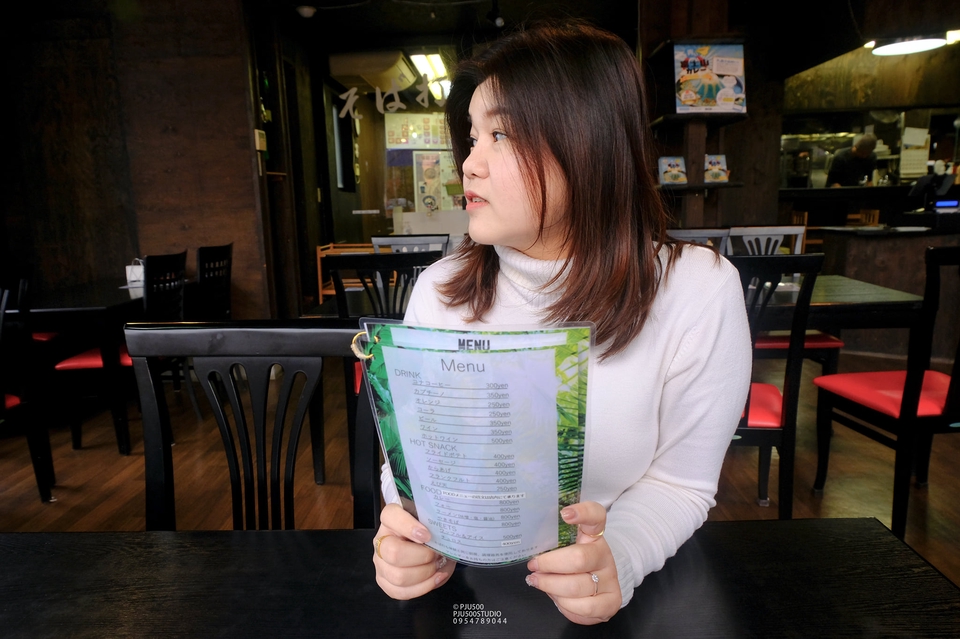 บล็อกเกอร์รีวิวร้านอาหาร ถือเมนูอาหารในมือ กำลังมองหาเมนูเพื่อรับรีวิวอาหารในร้านอาหาร