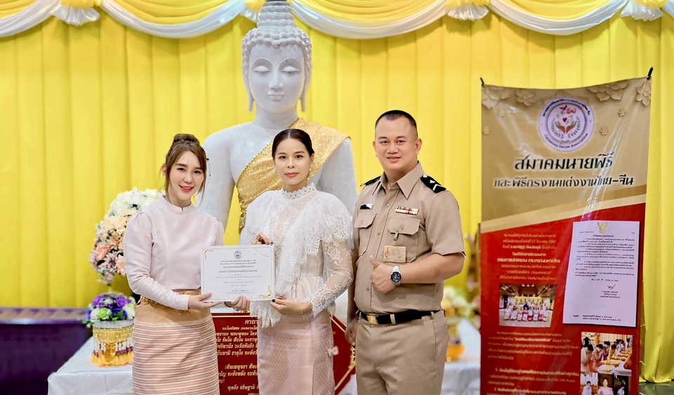 มอบใบประกาศ โดยมีพิธีกรงานแต่งมืออาชีพยืนคู่กับหญิงสาวในชุดสวยงาม ถ่ายภาพร่วมกับรูปปั้นพระพุทธรูป