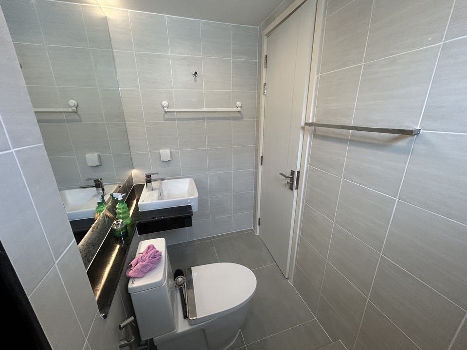 ปูกระเบื้องในห้องน้ำสวยงาม พื้นปูกระเบื้องสีเทา พร้อมผนังกระเบื้องเรียบๆ มีอ่างล้างหน้าและประตูห้องน้ำ เหมาะสำหรับผู้ที่ต้องการหาช่างปูกระเบื้อง ช่างกระเบื้องฝีมือดี รับเหมาปูกระเบื้อง ราคาถูก