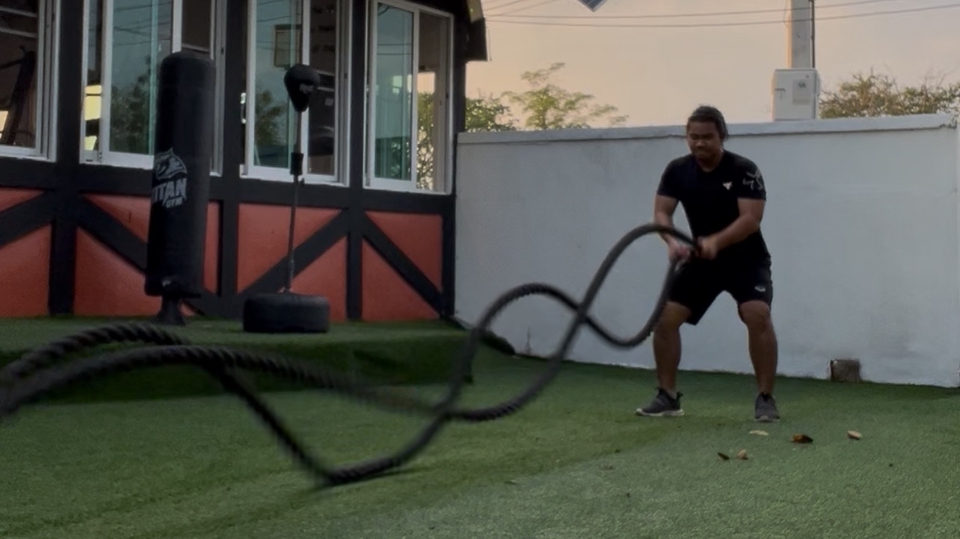 เทรนเนอร์ส่วนตัวกำลังออกกำลังกายโดยใช้เชือกออกกำลังกายในสวน พร้อมหาเทรนเนอร์ฟิตเนสใกล้บ้านเพื่อเทรนลดน้ำหนัก ปรึกษาเทรนเนอร์ฟรีแลนซ์เกี่ยวกับการเทรนลดน้ำหนัก รับสอนออกกำลังกายส่วนตัวแบบออนไลน์และที่บ้าน